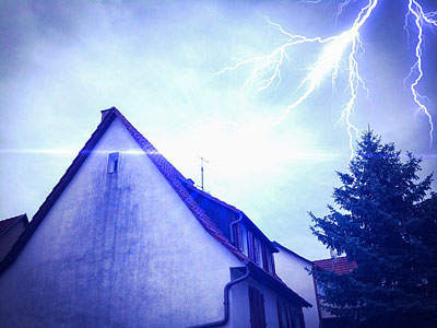 Ein Haus unter einem stürmischen Himmel mit Blitzschlägen.